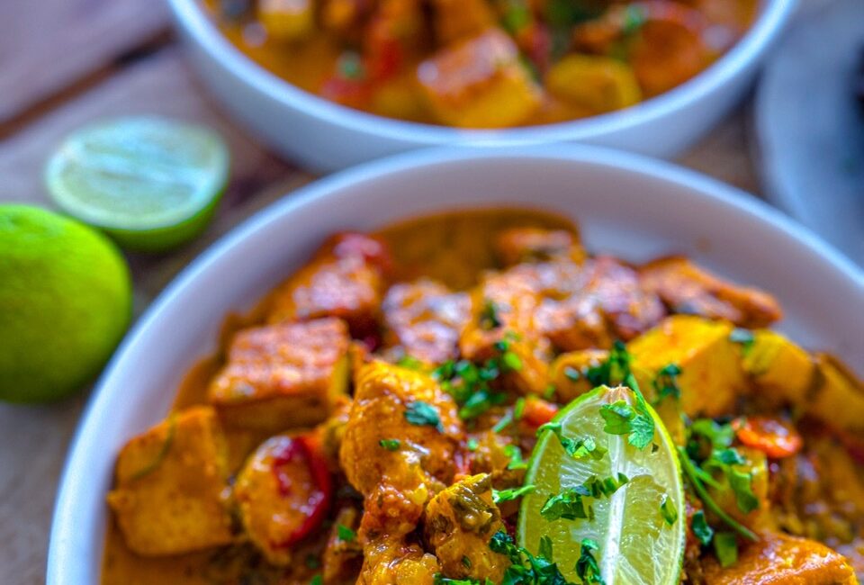 Bowl of creamy chicken and tofu tikka masala served with crispy onion bhajis and brown rice