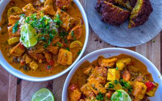 Bowl of creamy chicken and tofu tikka masala served with crispy onion bhajis and brown rice