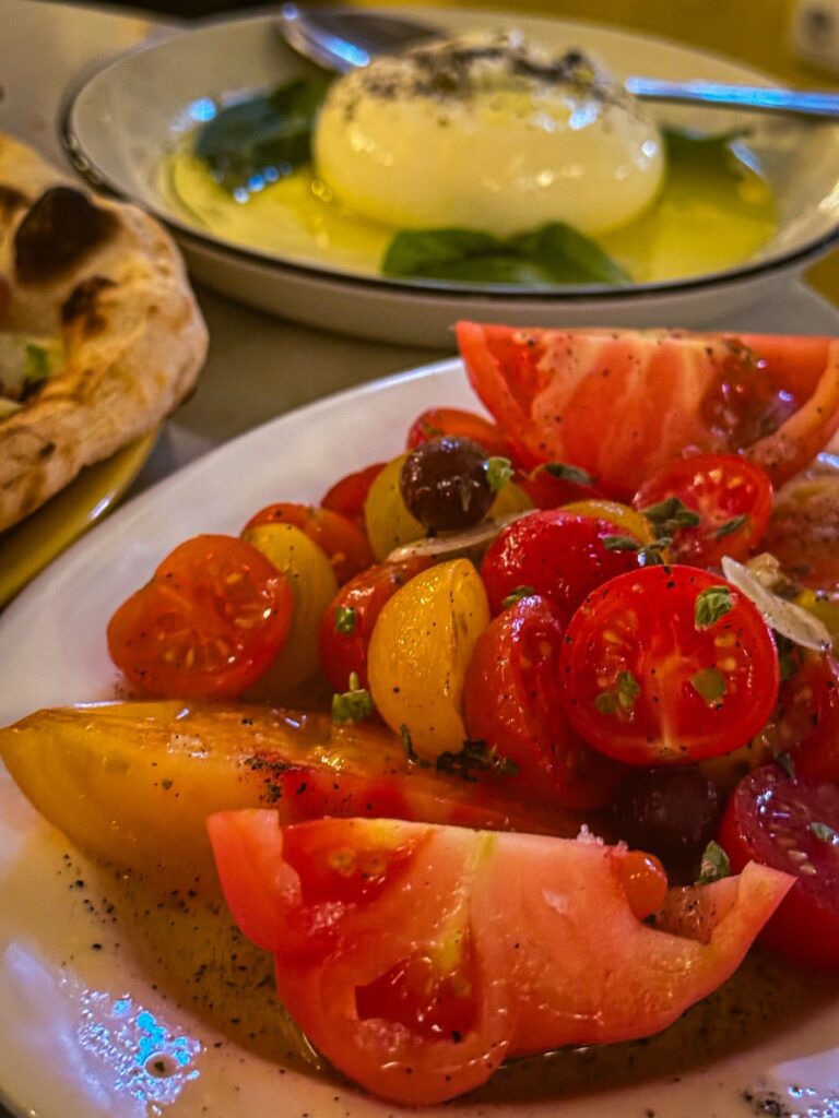Simple tomato and burrata salad, an example of how travel influences cooking by teaching restraint and the beauty of three perfect ingredients.