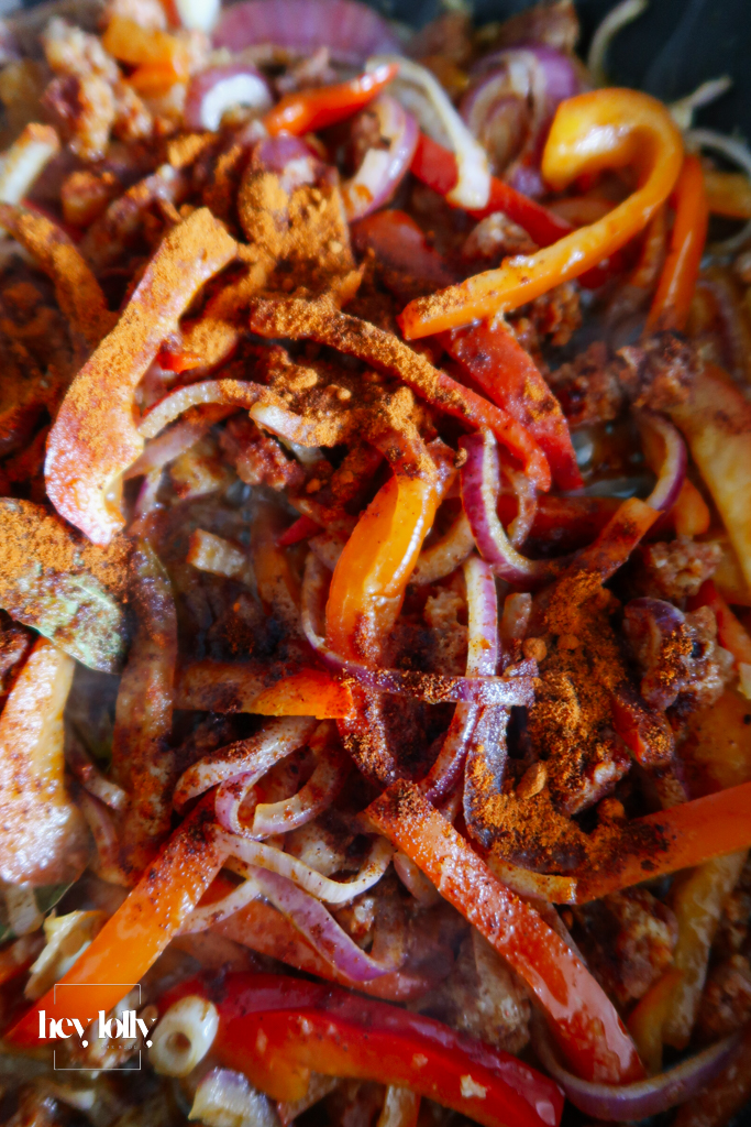 Veg base for baked cod with chorizo with tomatoes, peppers, onion and lemon. Close up of spices