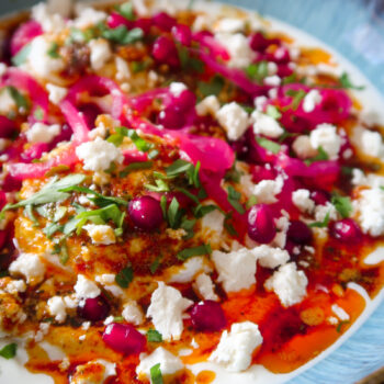 Bowl of Turkish eggs topped with spiced butter, pomegranate, feta and herbs
