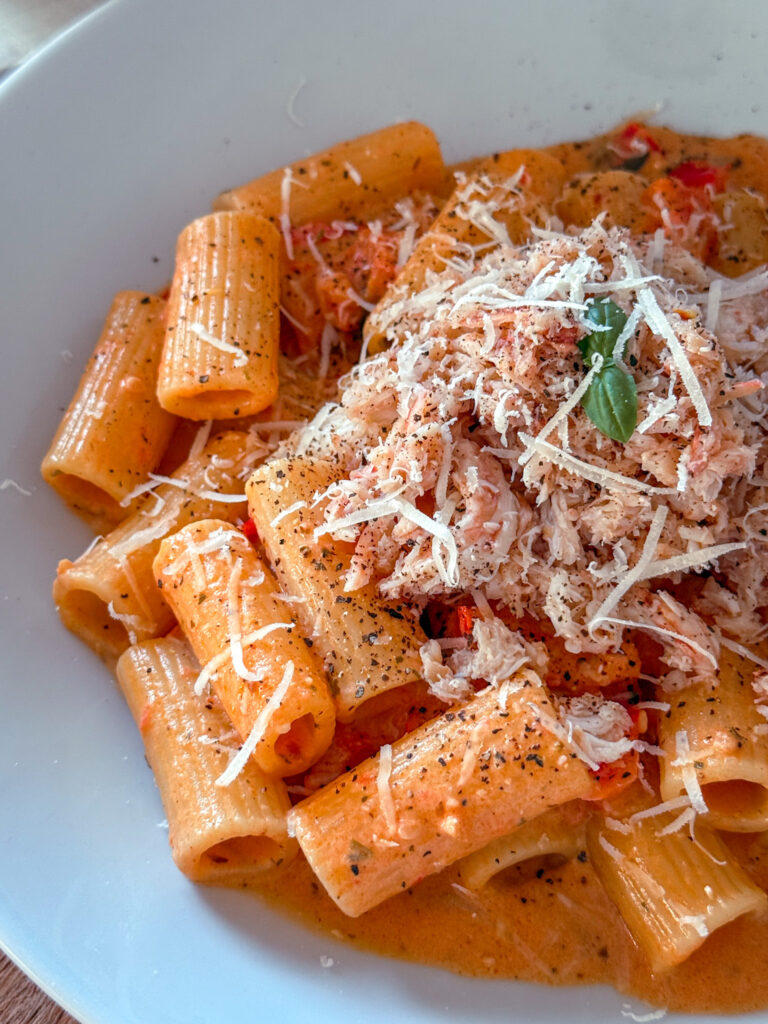 Bowl of quick crab and tomato pasta with, Parmesan and basil.