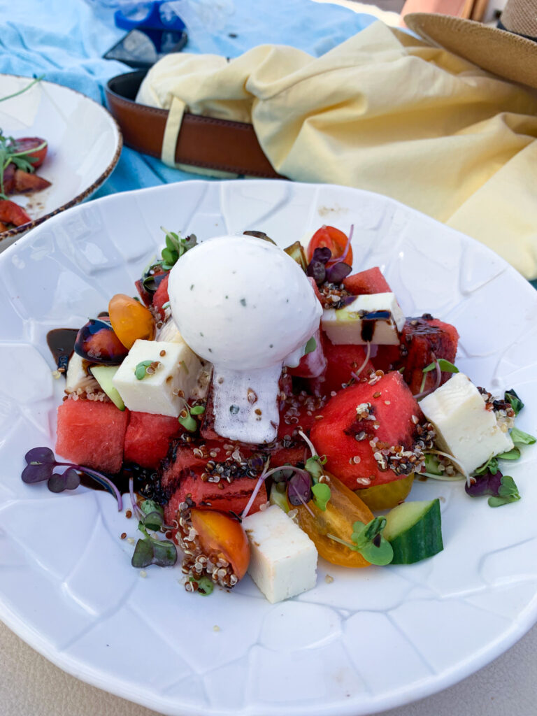 Colourful summer salad with watermelon, feta, quinoa, and yoghurt cream, showing how travel influences cooking with improvisation and bold flavours.