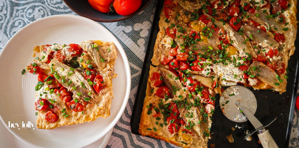 Overhead shot of a caramelised shallot and tomato tart glistening under golden puff pastry