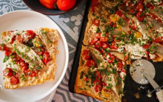 Overhead shot of a caramelised shallot and tomato tart glistening under golden puff pastry