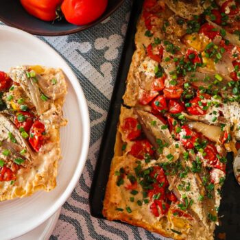 Overhead shot of a caramelised shallot and tomato tart glistening under golden puff pastry