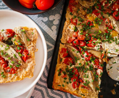 Overhead shot of a caramelised shallot and tomato tart glistening under golden puff pastry