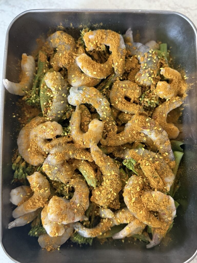 Close-up of prawns coated in spices sauce with charred broccoli.
