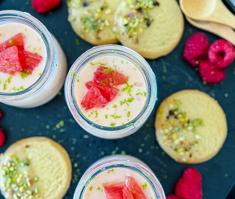 Silky grapefruit posset in glass ramekin with pistachio shortbread on the side