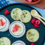 Silky grapefruit posset in glass ramekin with pistachio shortbread on the side