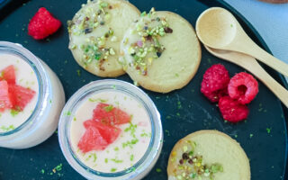 Silky grapefruit posset in glass ramekin with pistachio shortbread on the side