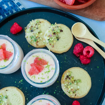 Silky grapefruit posset in glass ramekin with pistachio shortbread on the side