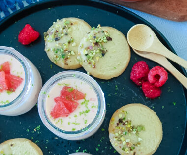 Silky grapefruit posset in glass ramekin with pistachio shortbread on the side