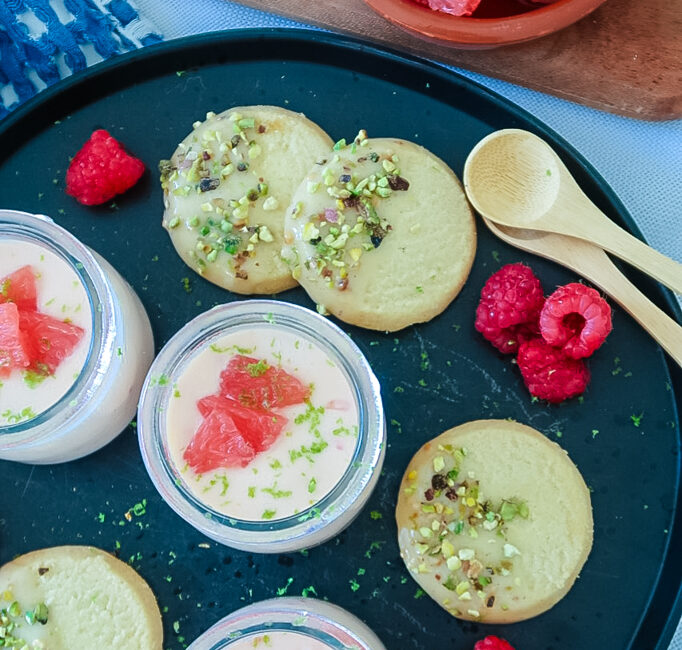 Silky grapefruit posset in glass ramekin with pistachio shortbread on the side