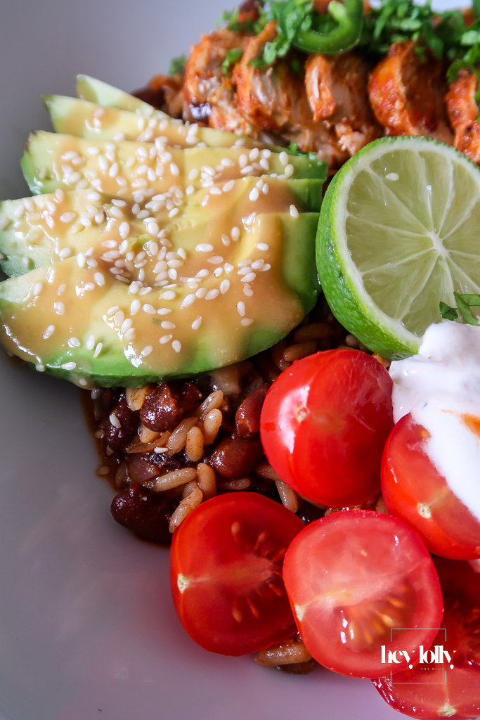 Colourful burrito bowl ingredients including chicken, rice, avocado, beans, sweetcorn, cheese, and lime.