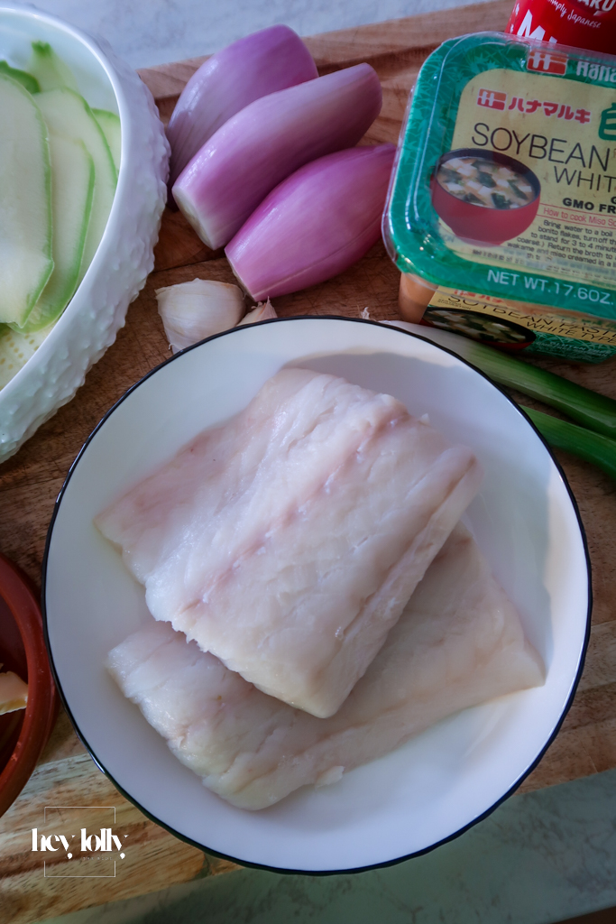 Raw cod fillets with miso butter ingredients on a board