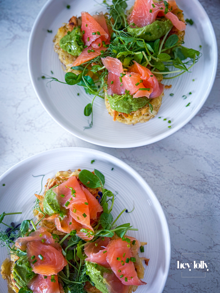Potato cakes topped with avocado cream and smoked salmon, finished with dill and lemon wedges.