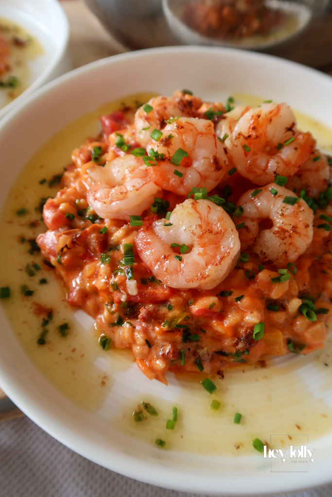 Creamy king prawn tomato risotto topped with seared prawns, chives, and olive oil drizzle