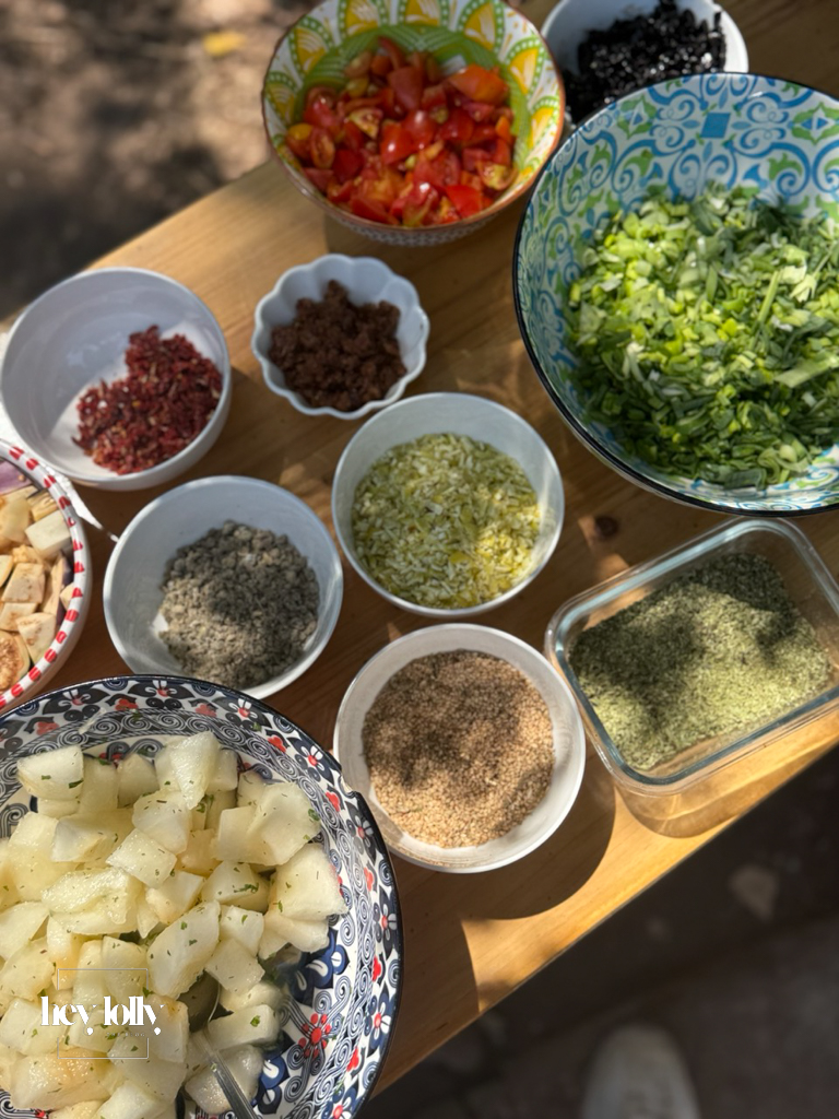 Group preparing fresh vegetables at rustic outdoor tables at Slow Life Family Farm, Siracusa.