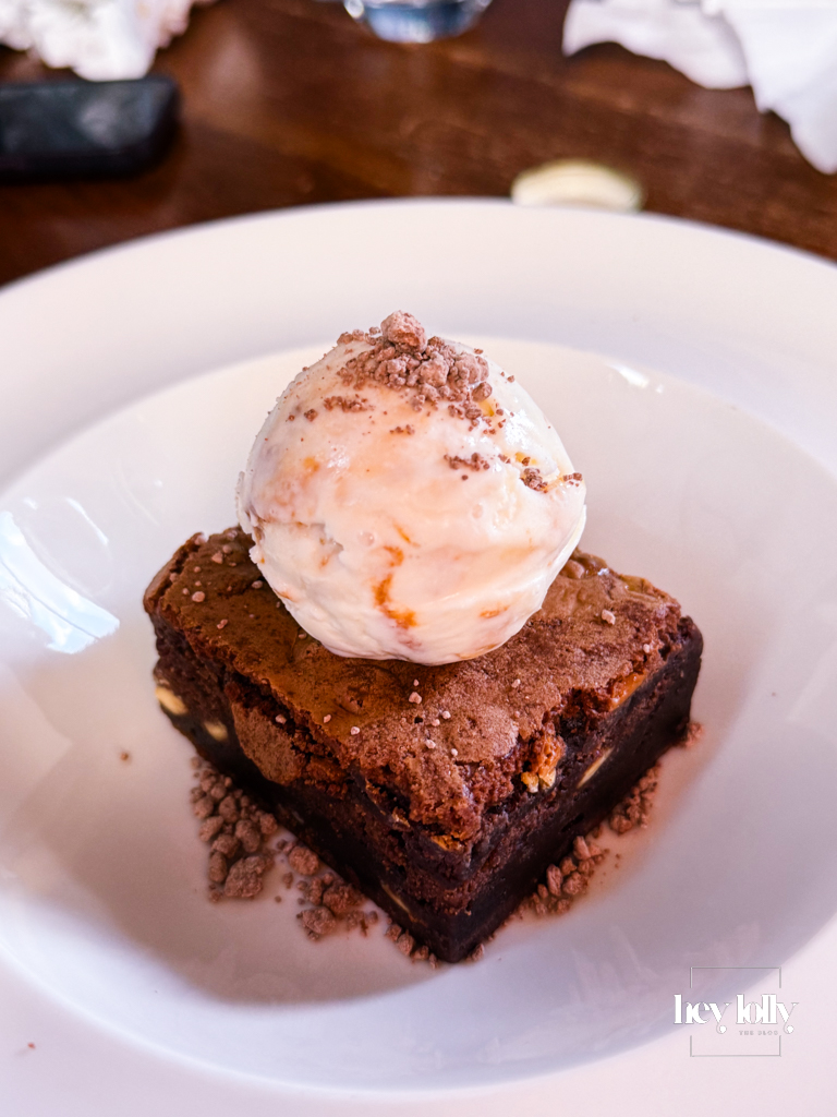 Chocolate brownie with crisp edges and gooey centre served with cream — Sunday lunch Nottingham dessert highlight.