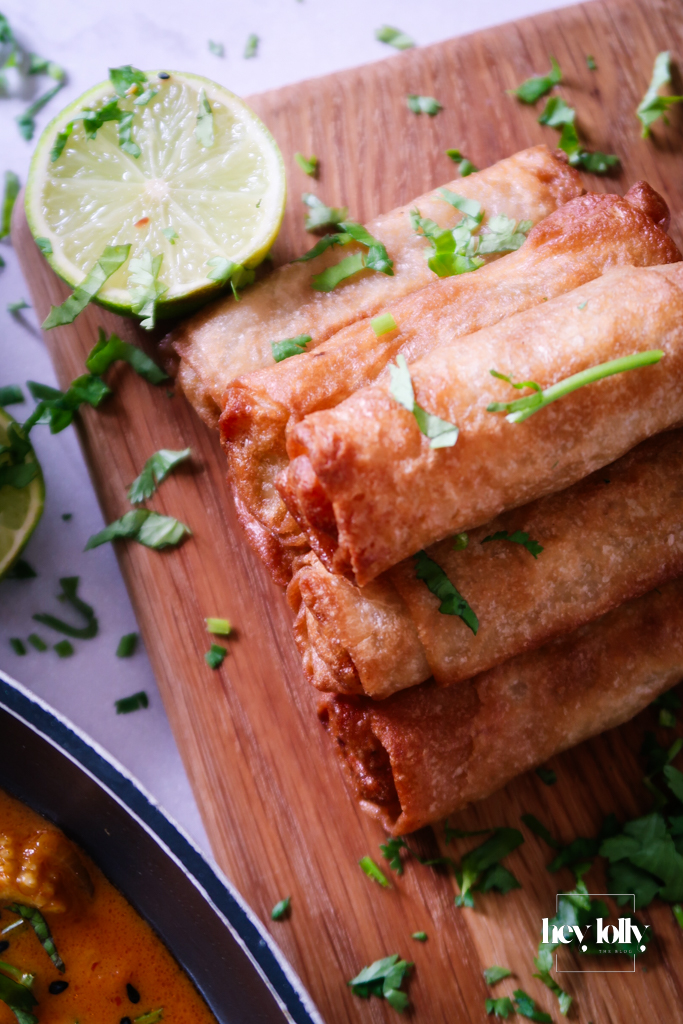 Close-up of Thai Red King Prawn curry showing prawns in creamy coconut-red sauce with spring rolls
