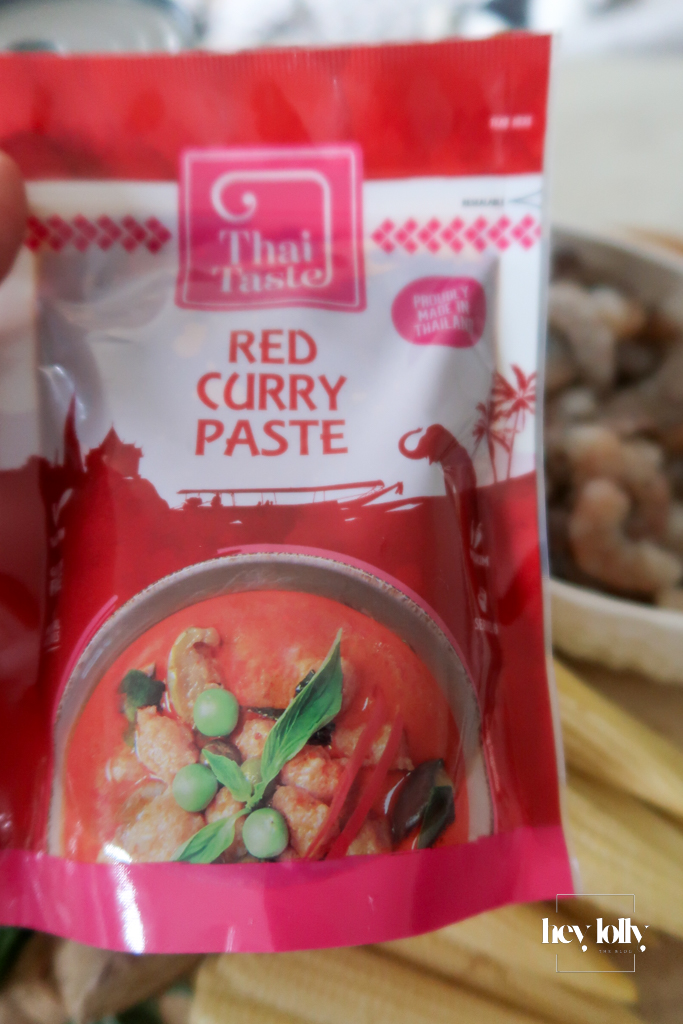 Spoon of red curry paste sizzling in hot oil for Thai Red King Prawn curry.