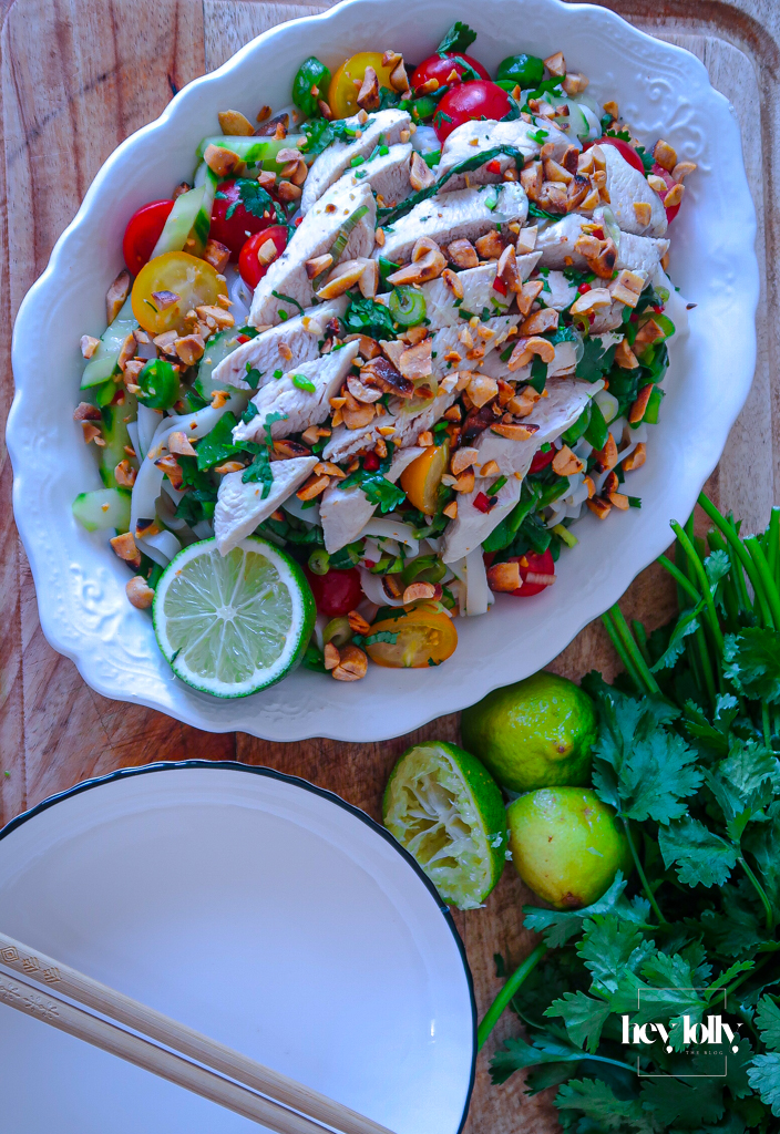 Plated Thai poached chicken salad with glass noodles, fresh herbs, and crushed peanuts.