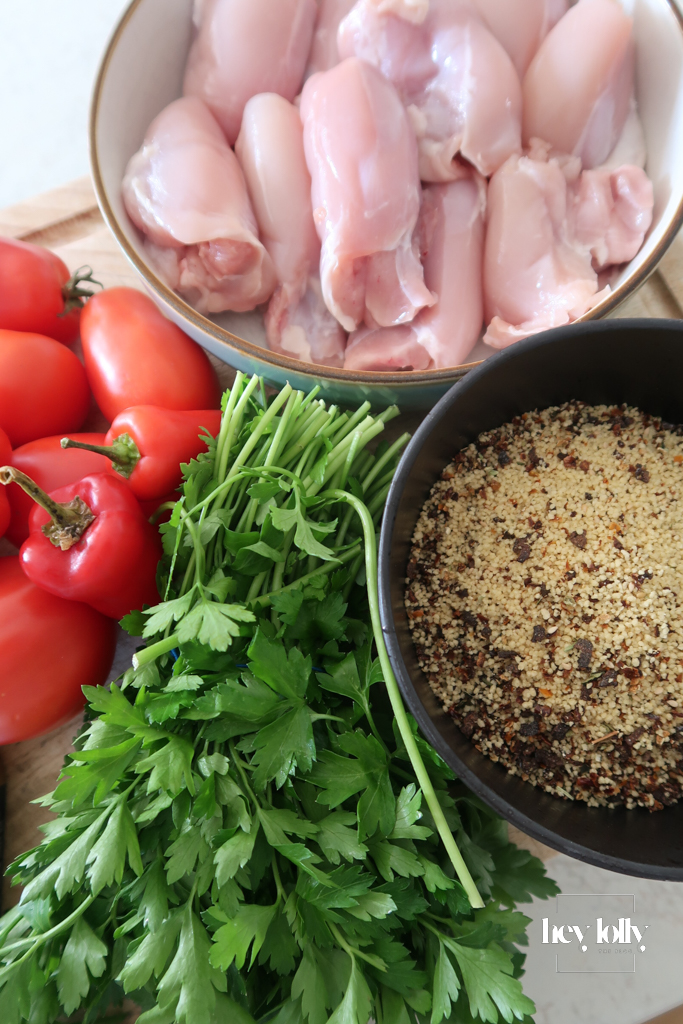 Za’atar Chicken Thighs mise en place with cherry tomatoes, anchovies, chilli, and herbs arranged on board