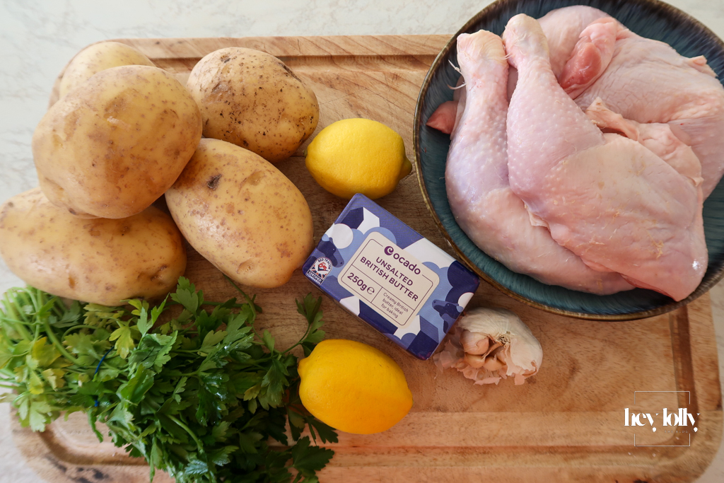 ngredients for garlic butter roast chicken with lemon cavolo nero, crispy potatoes, Dijon mustard, and fresh garlic on a kitchen counter.