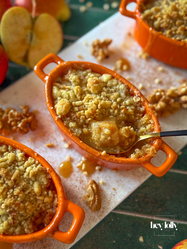 Spoon breaking the sandy lid of apple and miso caramel crumble to reveal jammy apples.
