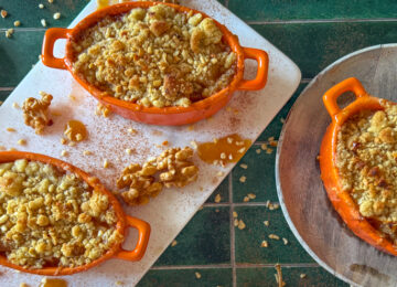 Apple and miso caramel crumble in white ramekins, bronzed sandy topping and glossy caramel drizzle.