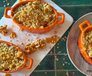 Apple and miso caramel crumble in white ramekins, bronzed sandy topping and glossy caramel drizzle.