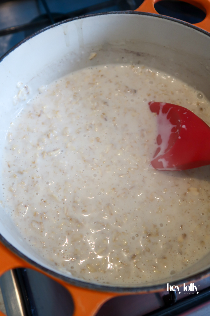 Oats simmering in milk in a saucepan – Oats cooking gently in Tom Parker’s unhomogenised milk for maple-pear & pecan porridge