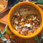 Close-up bowl of mushroom gnocchi soup with bronze mushrooms, thyme and parmesan shavings, steam rising.