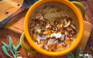 Close-up bowl of mushroom gnocchi soup with bronze mushrooms, thyme and parmesan shavings, steam rising.
