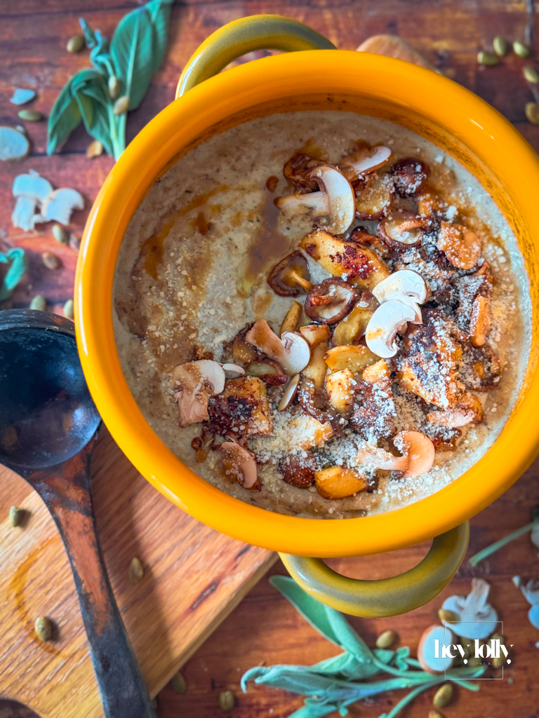 Overhead bowl of mushroom gnocchi soup with torn bread and a small pot of grated parmesan.