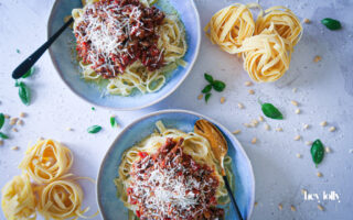 rich beef ragu plated in bowls with tagliatelle and freshly shaved parmesan
