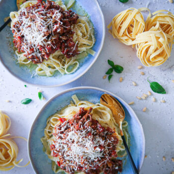 rich beef ragu plated in bowls with tagliatelle and freshly shaved parmesan