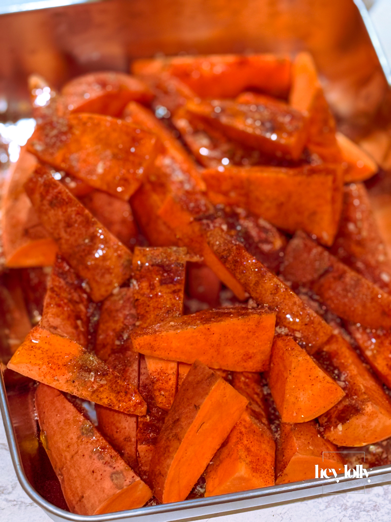 Seasoned fries spaced out on a lined tray, ready for the oven.