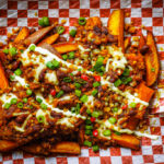 loaded sweet potato fries with sour cream and herbs, ready to share.