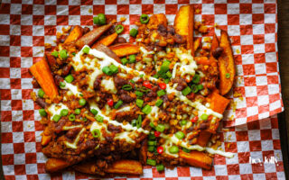 loaded sweet potato fries with sour cream and herbs, ready to share.