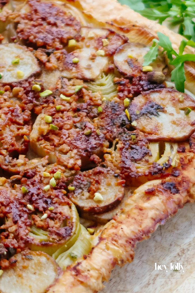 Slice of Jerusalem artichoke and leek tart with truffle pesto served with a crisp green salad