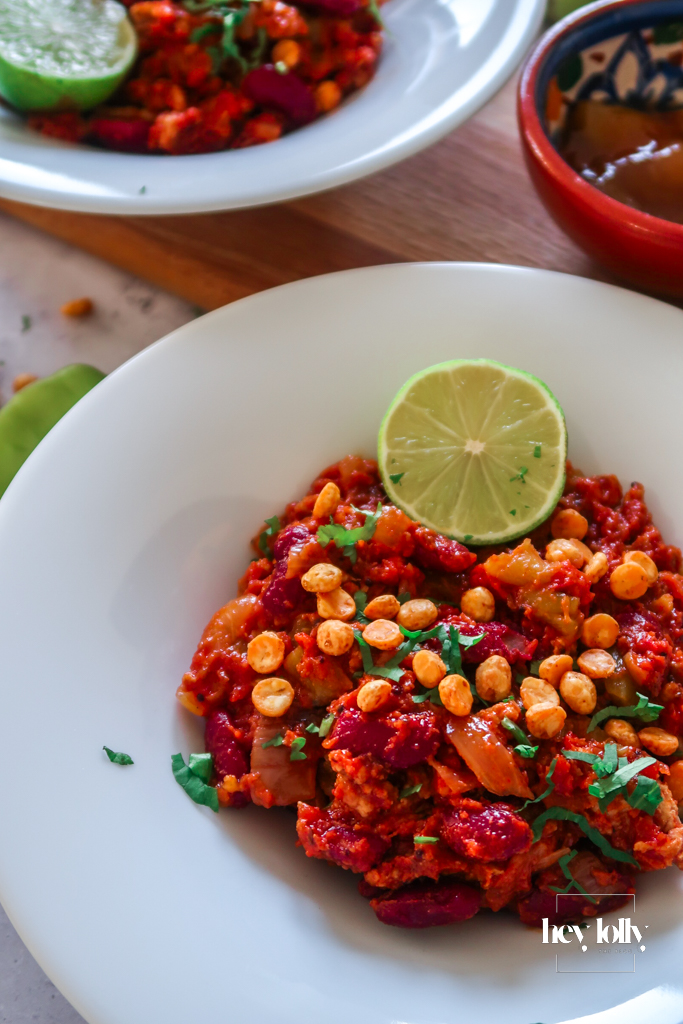 Bowl of chicken and kidney bean keema served with crisp poppadums and a side of mango chutney