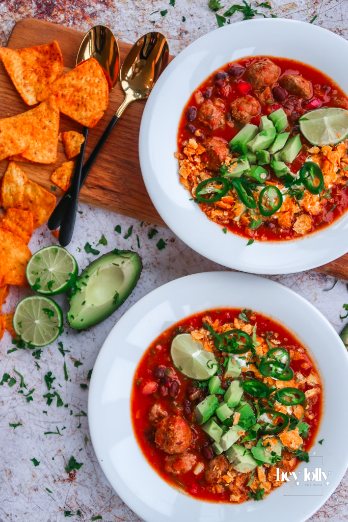 Two bowls of Cowboy Taco Soup on the table, extra lime wedges and chips on the side
