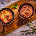overhead shot of bubbling pots of herby chesnut and cheddar beef cobbler