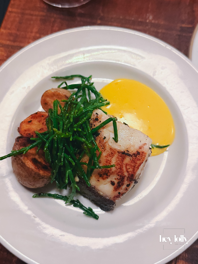 Seared halibut with samphire, Cornish potatoes and hollandaise on a white plate