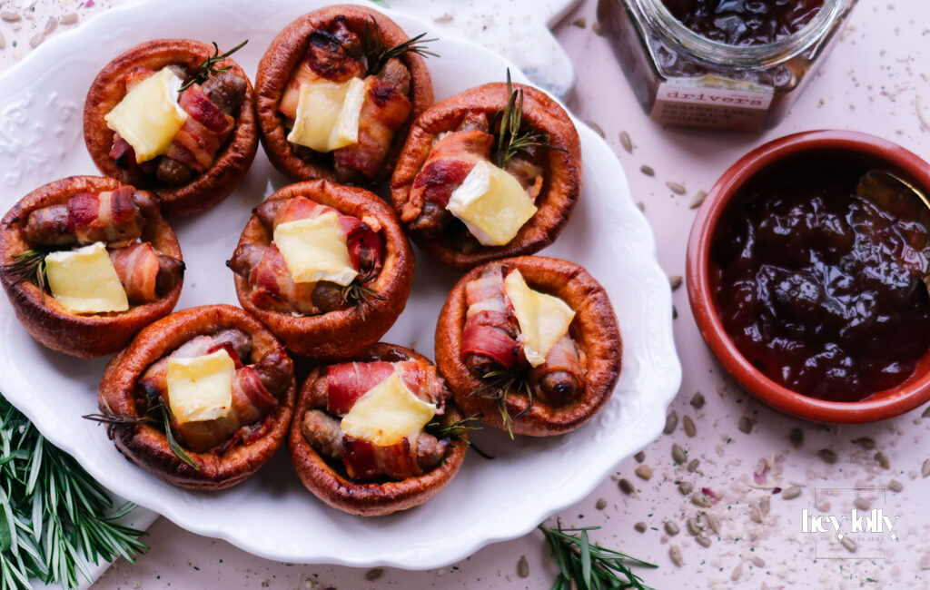 Pigs in blankets Yorkshire puddings with Brie and caramelised onion, festive platter scene.