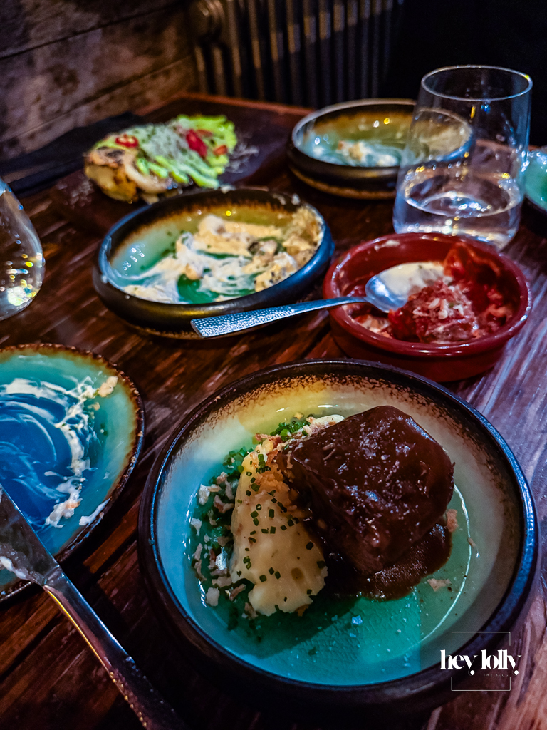 Carne estofada at Plates by Purnell’s – braised beef with mashed potato, gravy and chives in a deep green bowl on a wooden table.