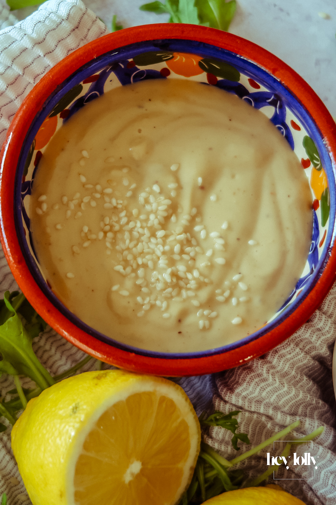 Pourable lemon tahini dressing in a small bowl with a spoon, ready to drizzle.