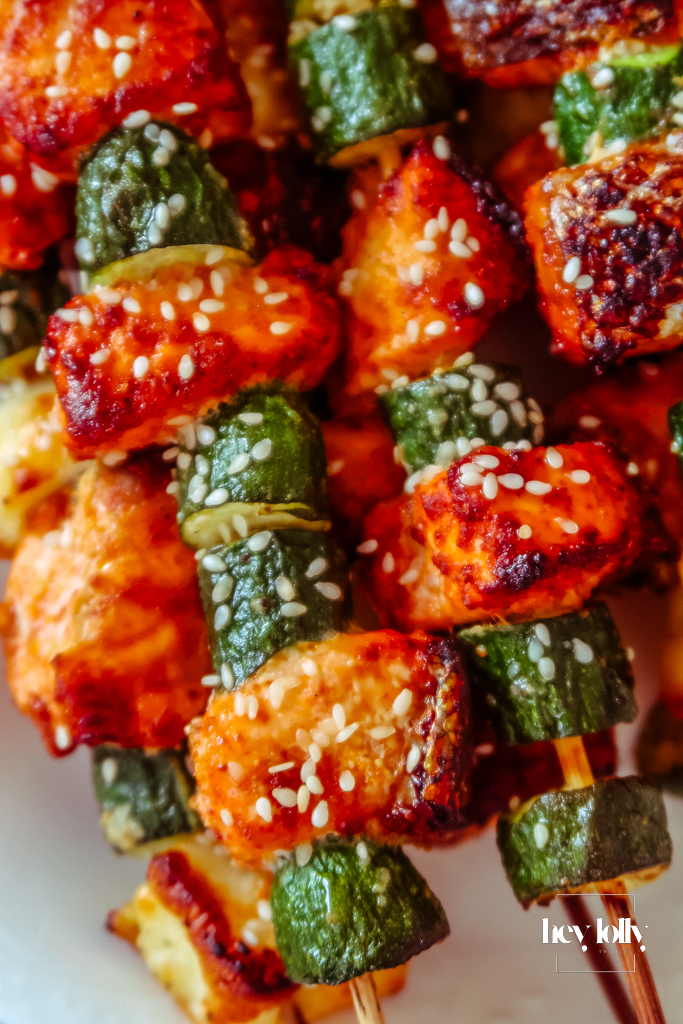 Close-up of flaky salmon with glossy courgette and bronzed halloumi on the skewer.